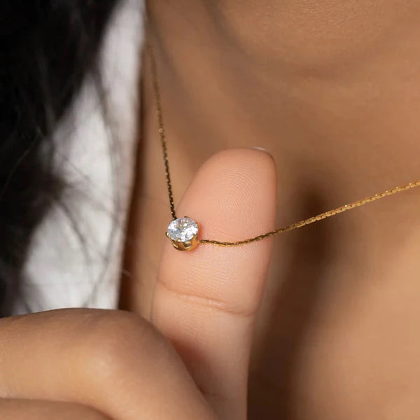 Close-up of a gold necklace with a diamond on a blurred background