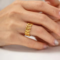 Gold leaf ring on a person's finger against a neutral background
