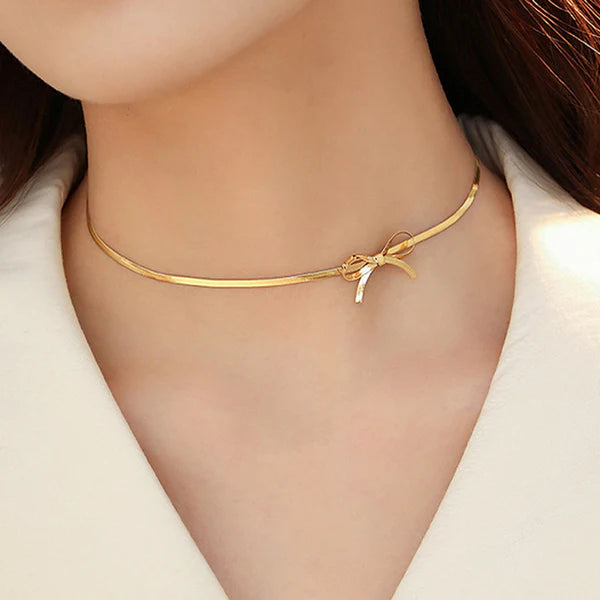 Gold necklace with a bow detail worn by a person
