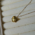 Gold necklace with a heart-shaped pendant on a white textured surface