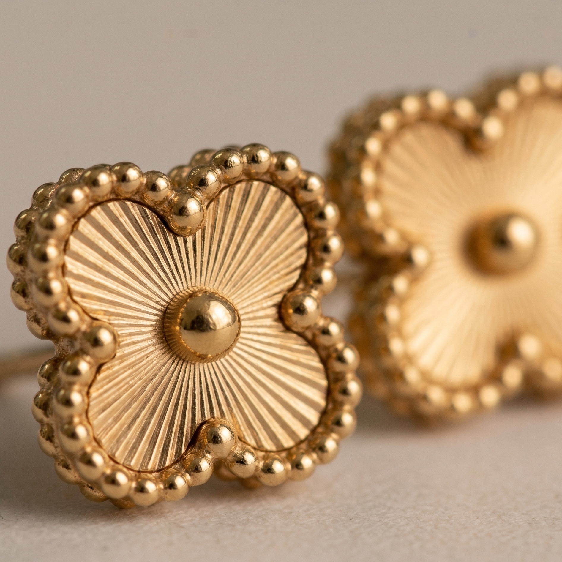 Gold heart-shaped earrings on a neutral background