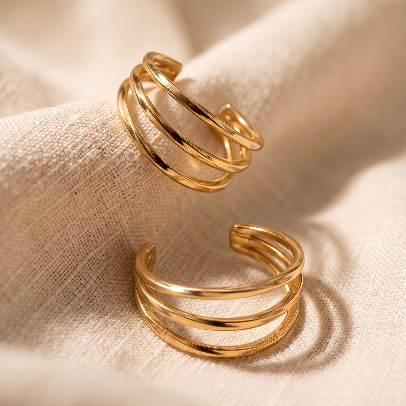 Two gold rings on a beige fabric background