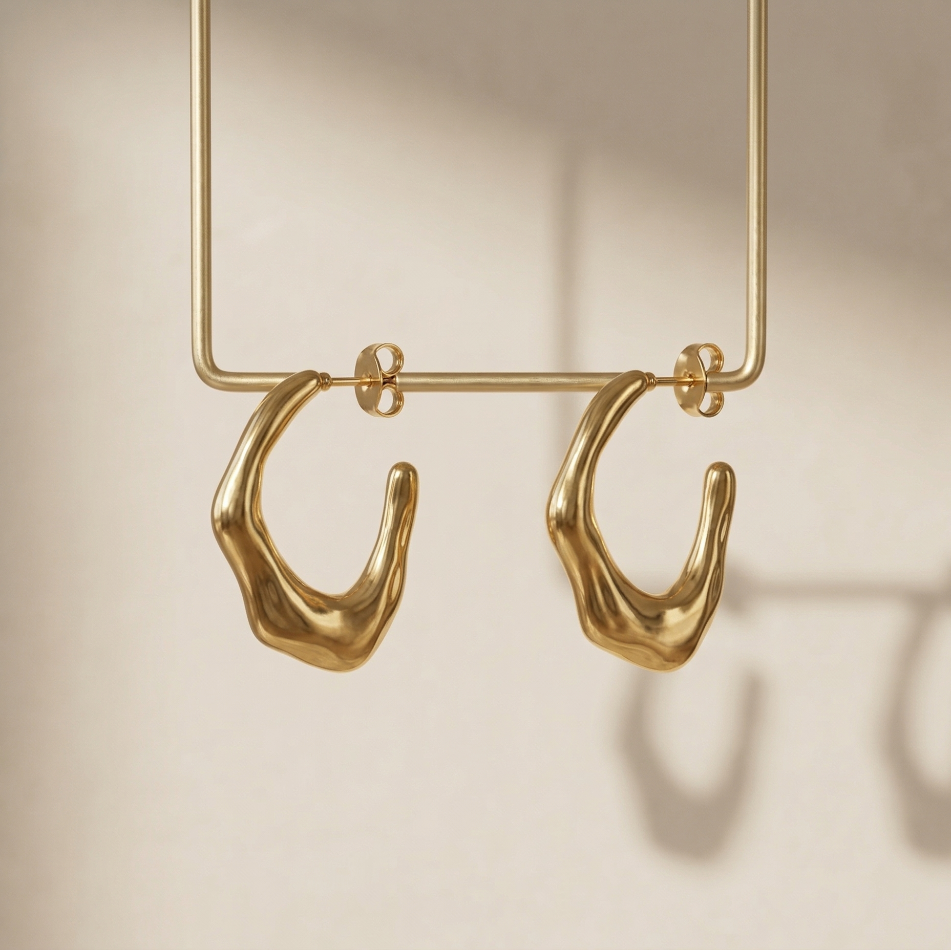 Gold hoop earrings on a beige background