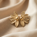Gold floral earrings on beige fabric