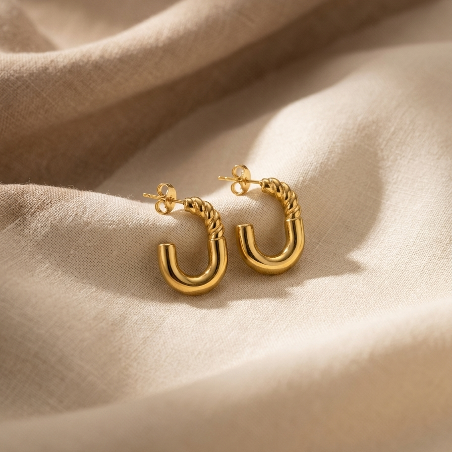 Gold hoop earrings on a beige fabric background