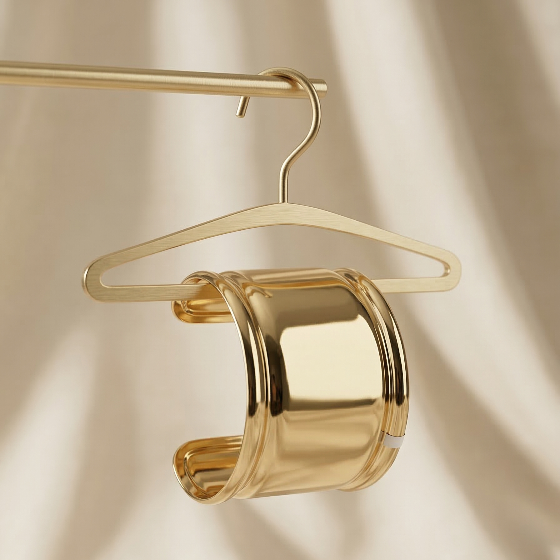 Gold bracelet on a gold hanger against a beige background