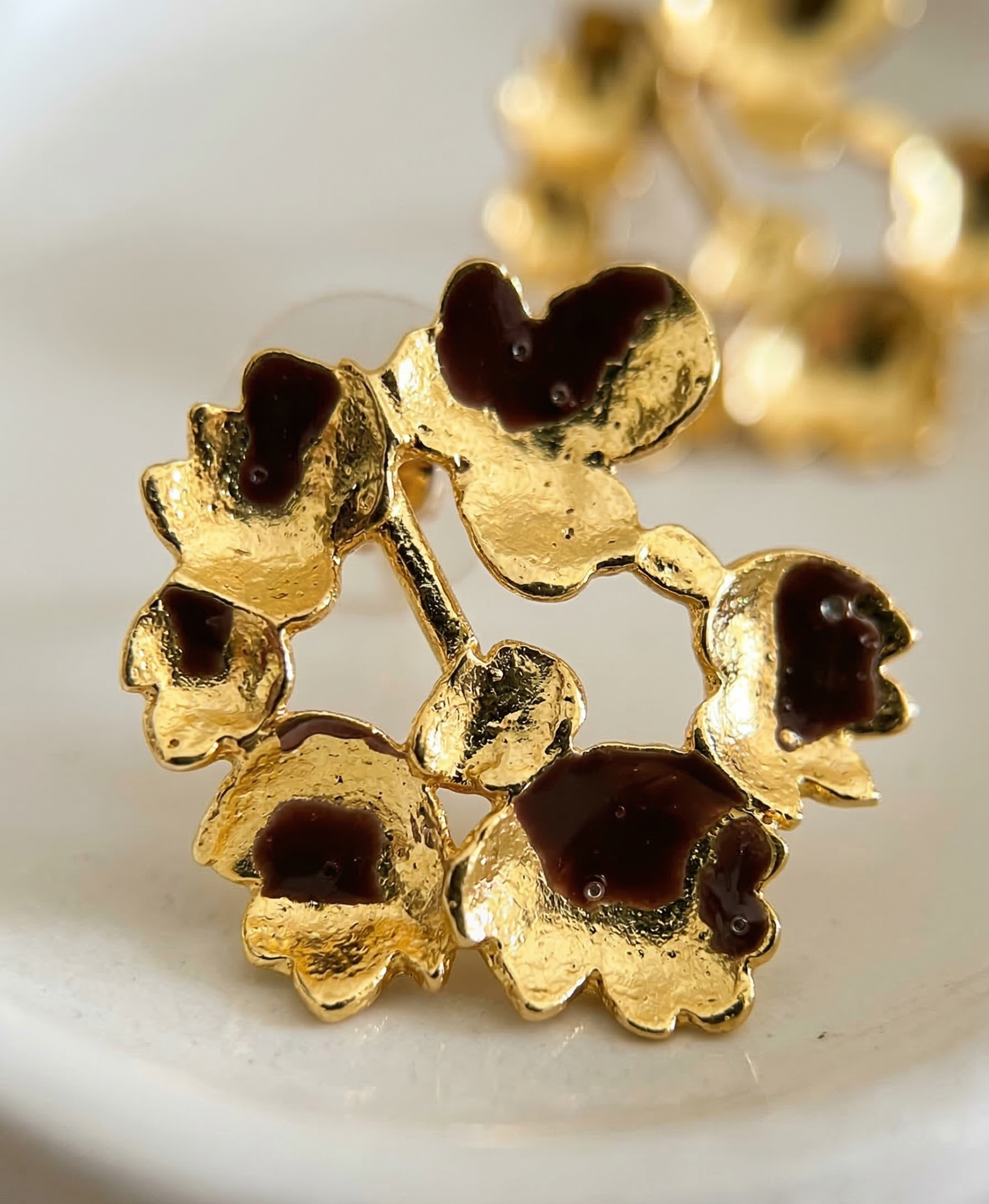 Gold floral brooch with dark centers on a white background