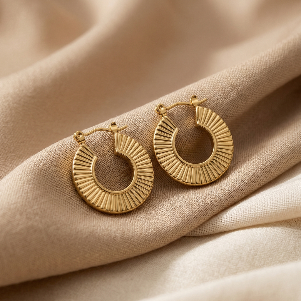 Gold hoop earrings on a beige fabric background