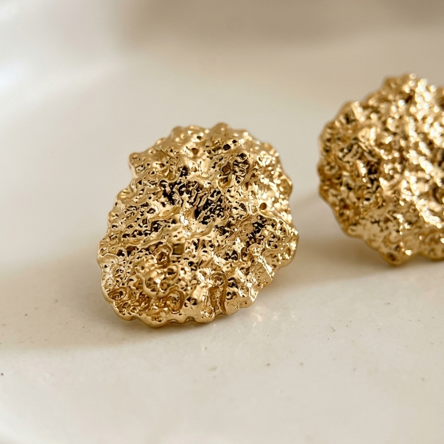 Gold textured earrings on a white dish
