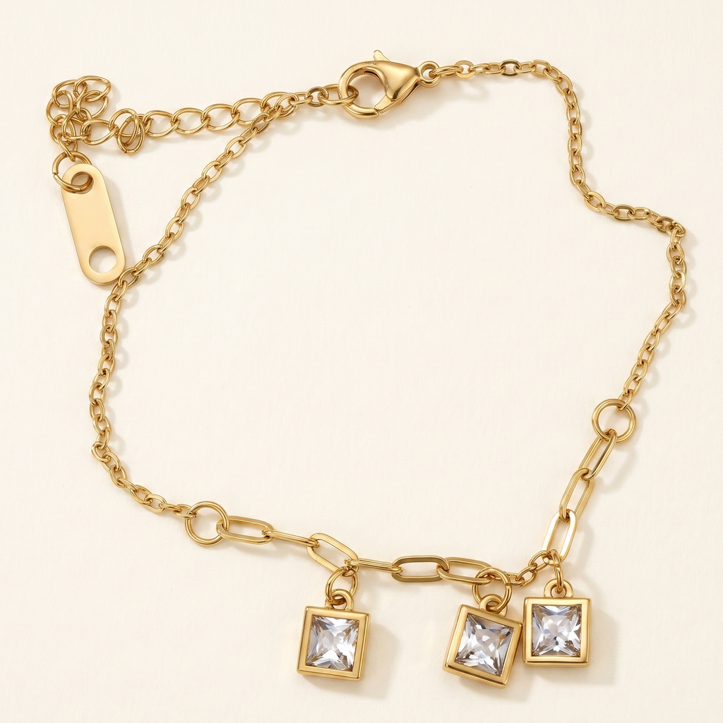 Gold bracelet with square charm on a beige background
