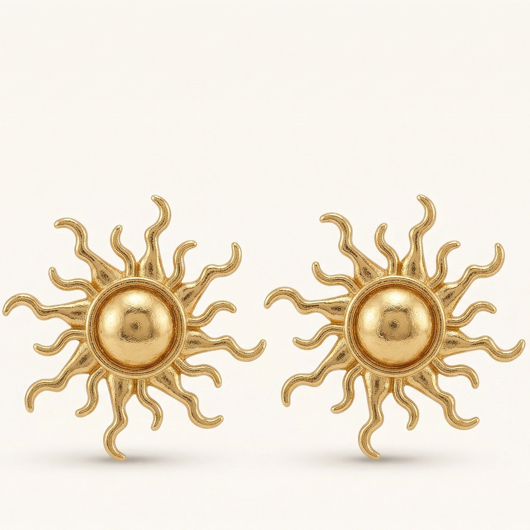 Pair of gold sun-shaped earrings on a white background