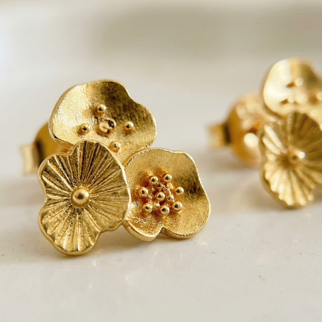 Gold floral earrings on a light background