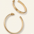 Gold hoop earrings on a light beige background