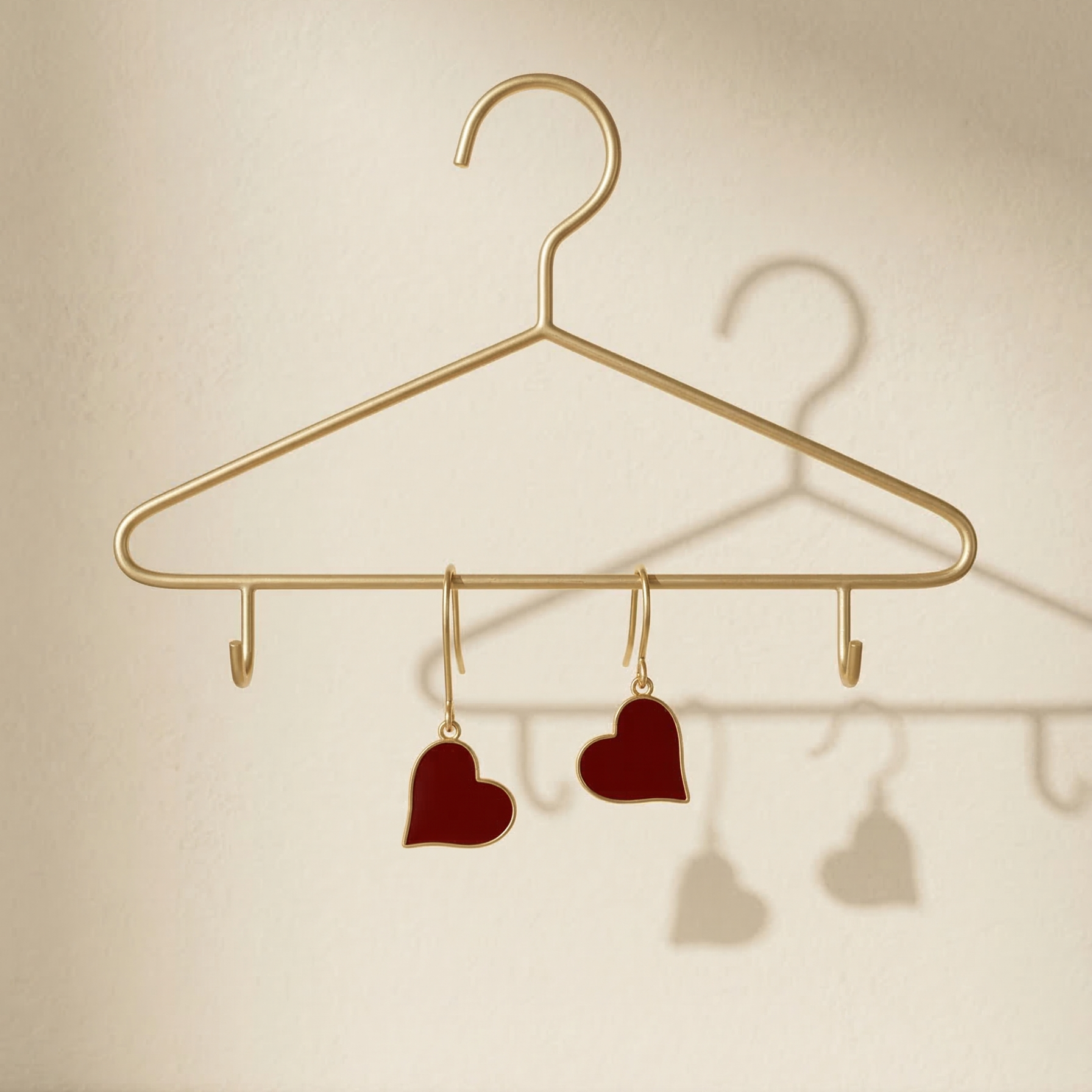 Gold hanger with heart-shaped hooks on a beige background