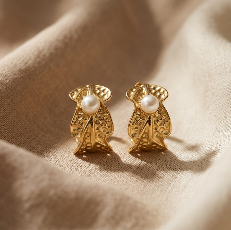 Gold earrings with pearl centers on a beige fabric background