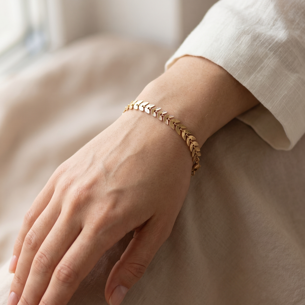Hand wearing a gold bracelet on a neutral background