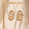 Gold hoop earrings with floral designs on a beige background