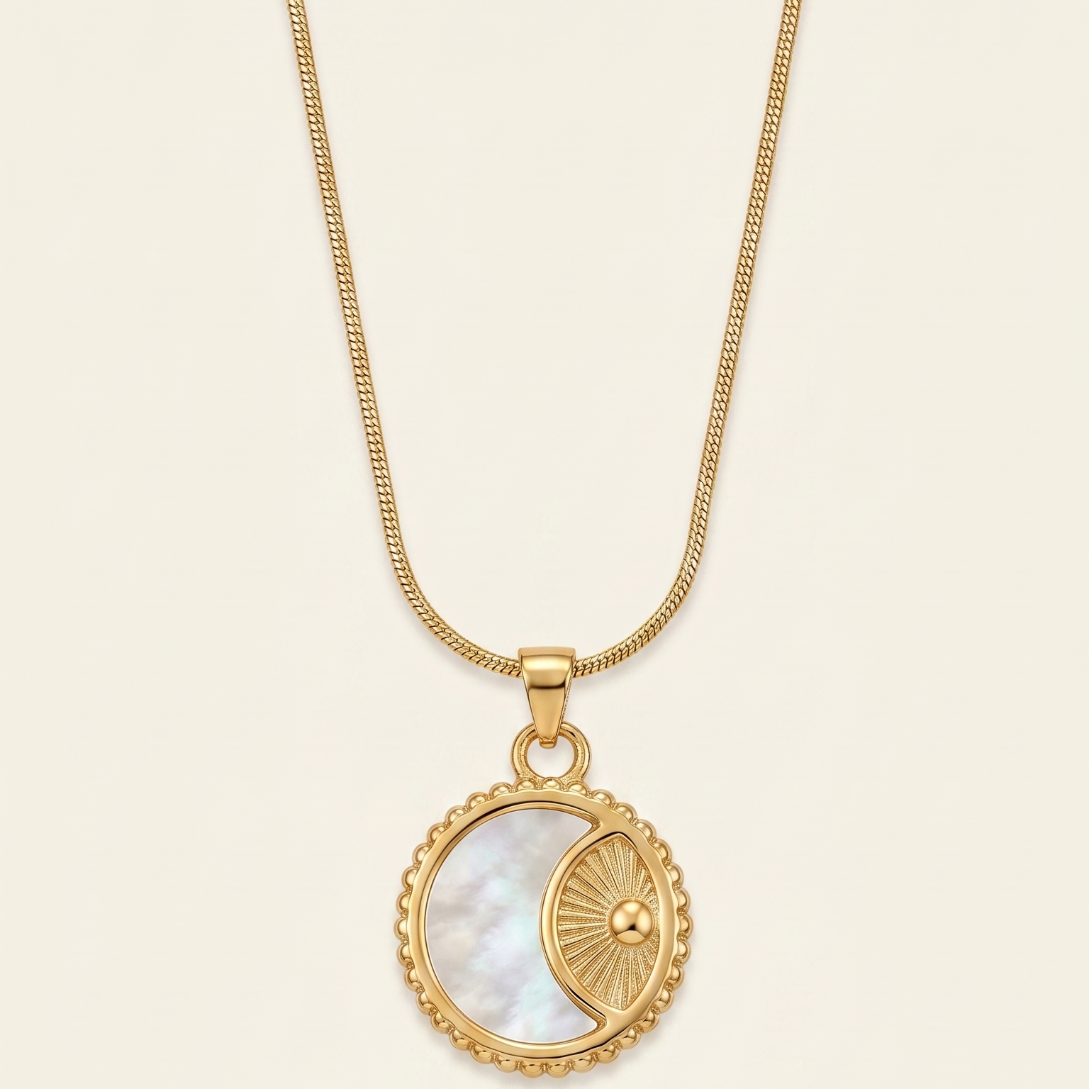 Gold necklace with a pendant featuring a circular design on a beige background
