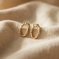 Gold hoop earrings on a beige fabric background