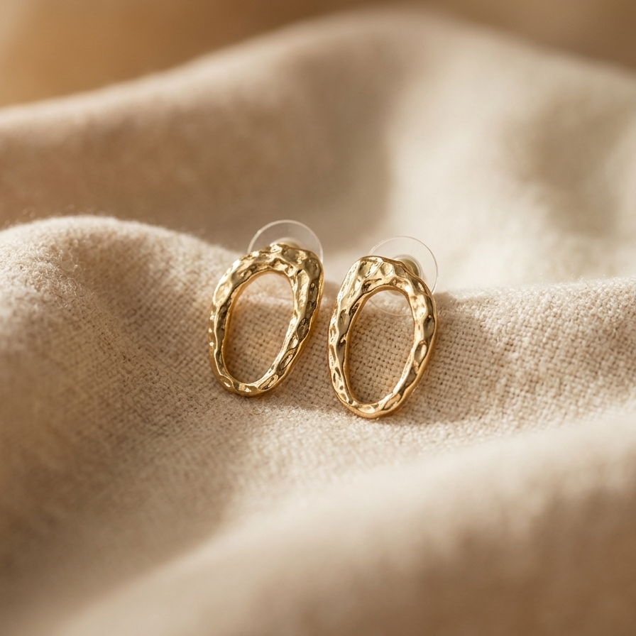 Gold hoop earrings on a beige fabric background