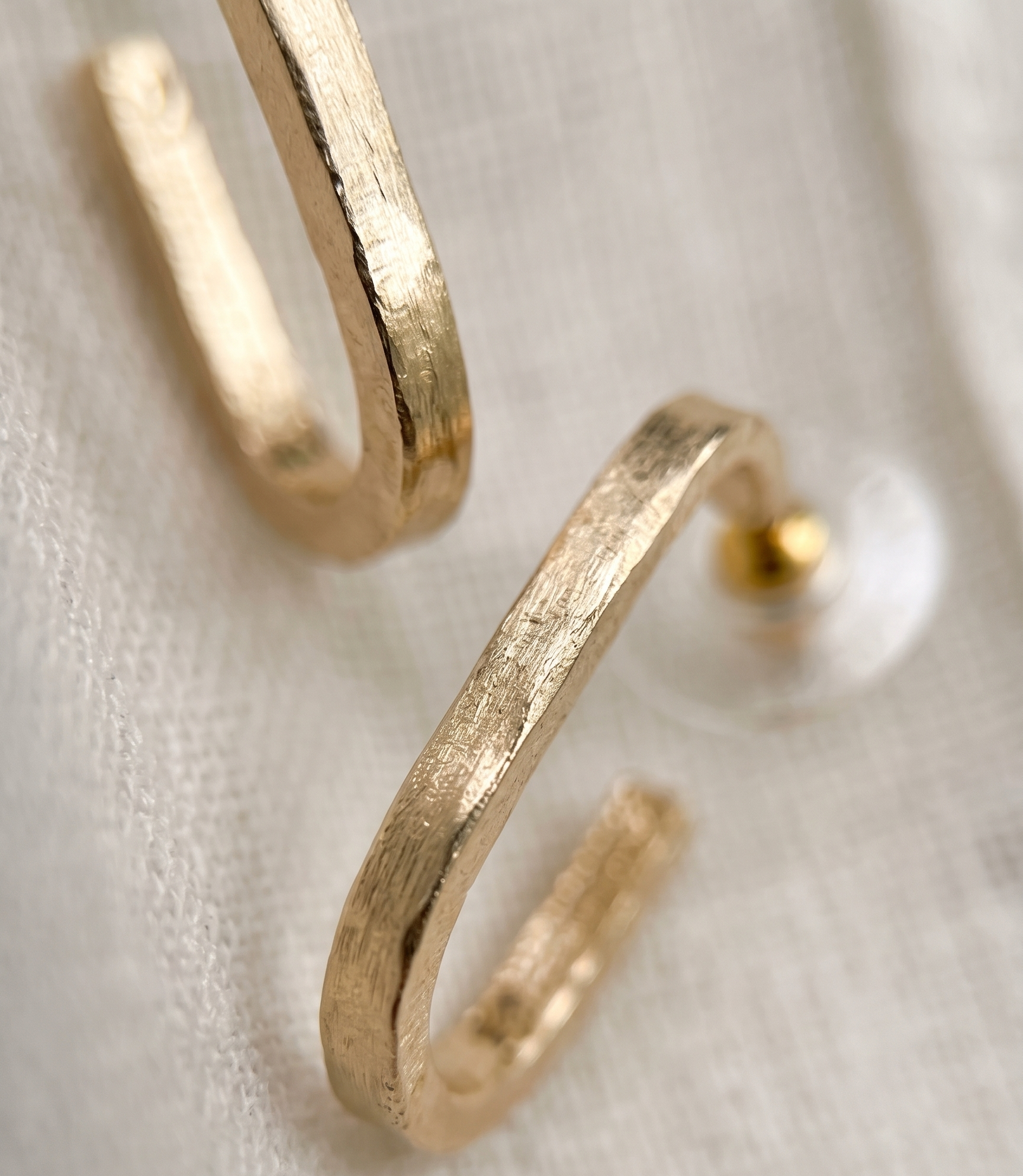 Gold hoop earrings on a light fabric background