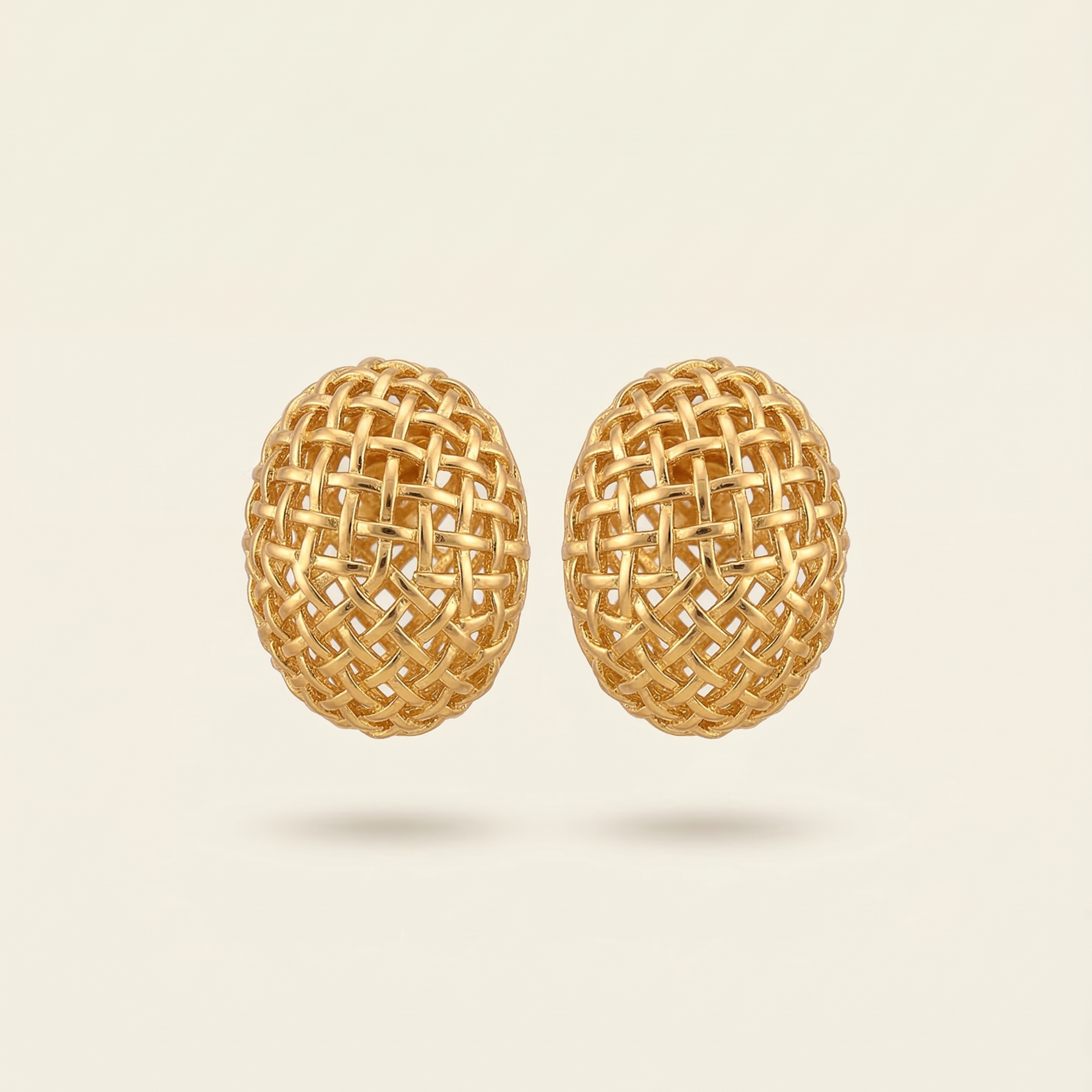 Pair of gold woven earrings on a beige background