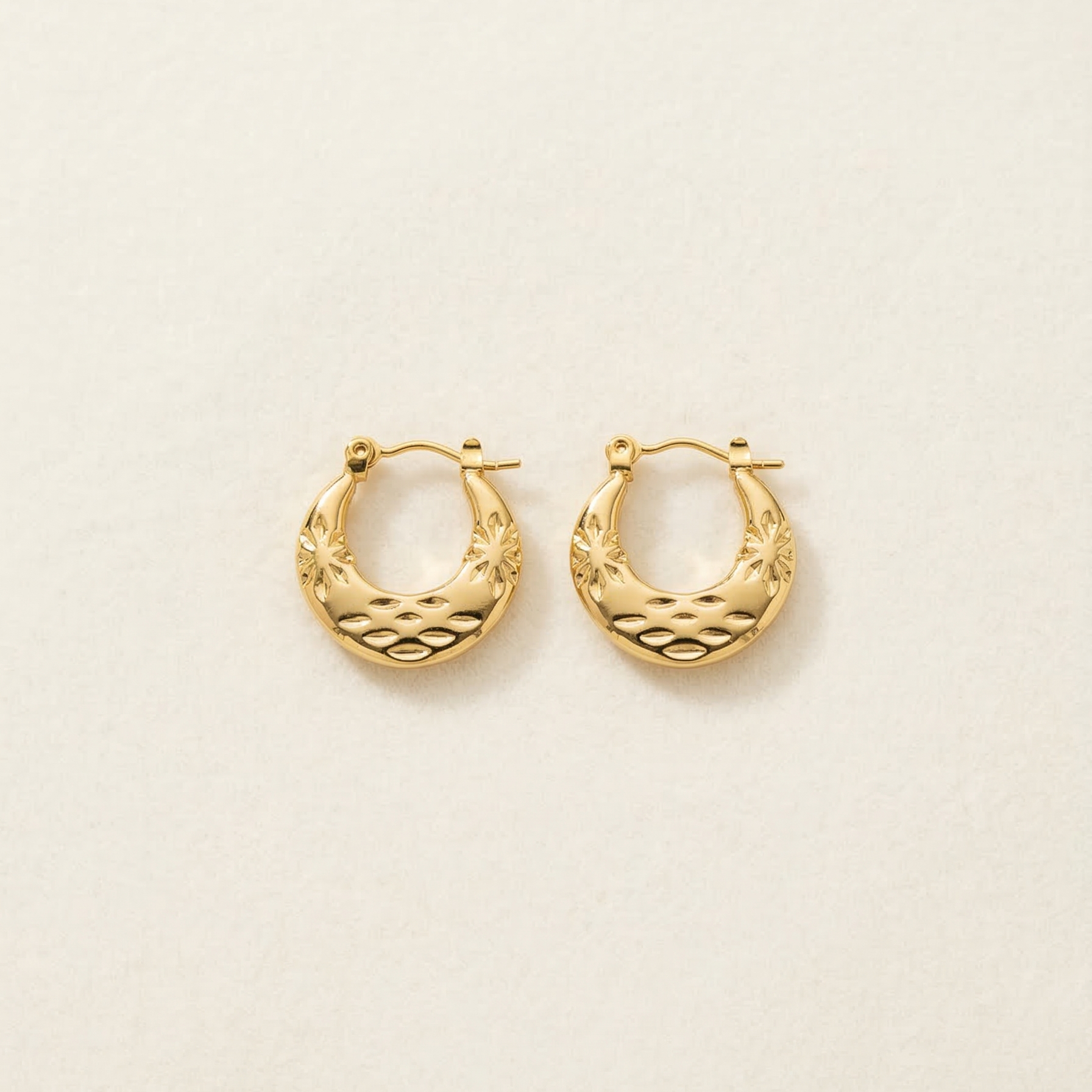 Gold hoop earrings on a light beige background