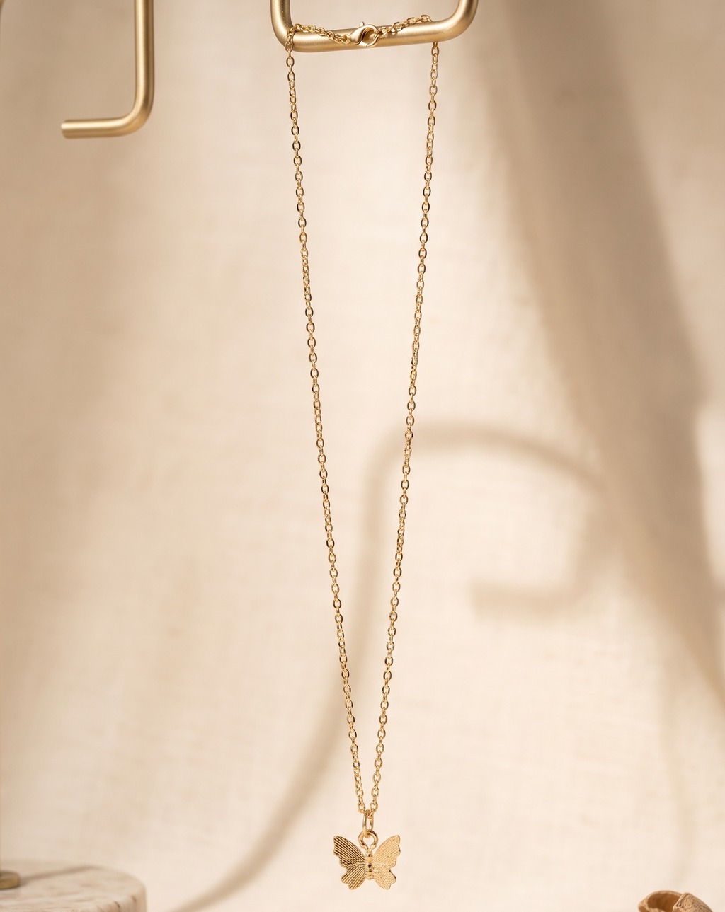 Gold butterfly necklace on a beige background