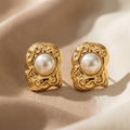 Gold earrings with pearl centers on a beige fabric background