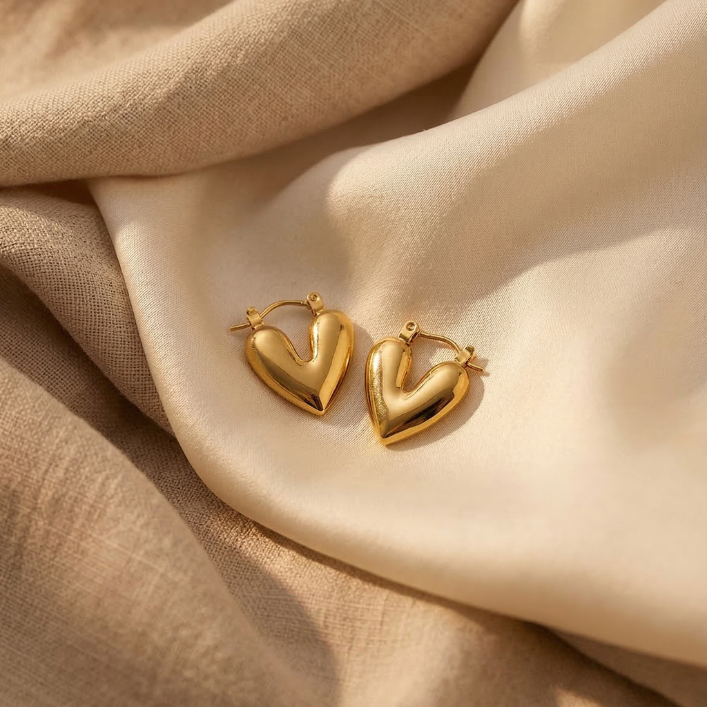 Gold heart-shaped earrings on beige fabric