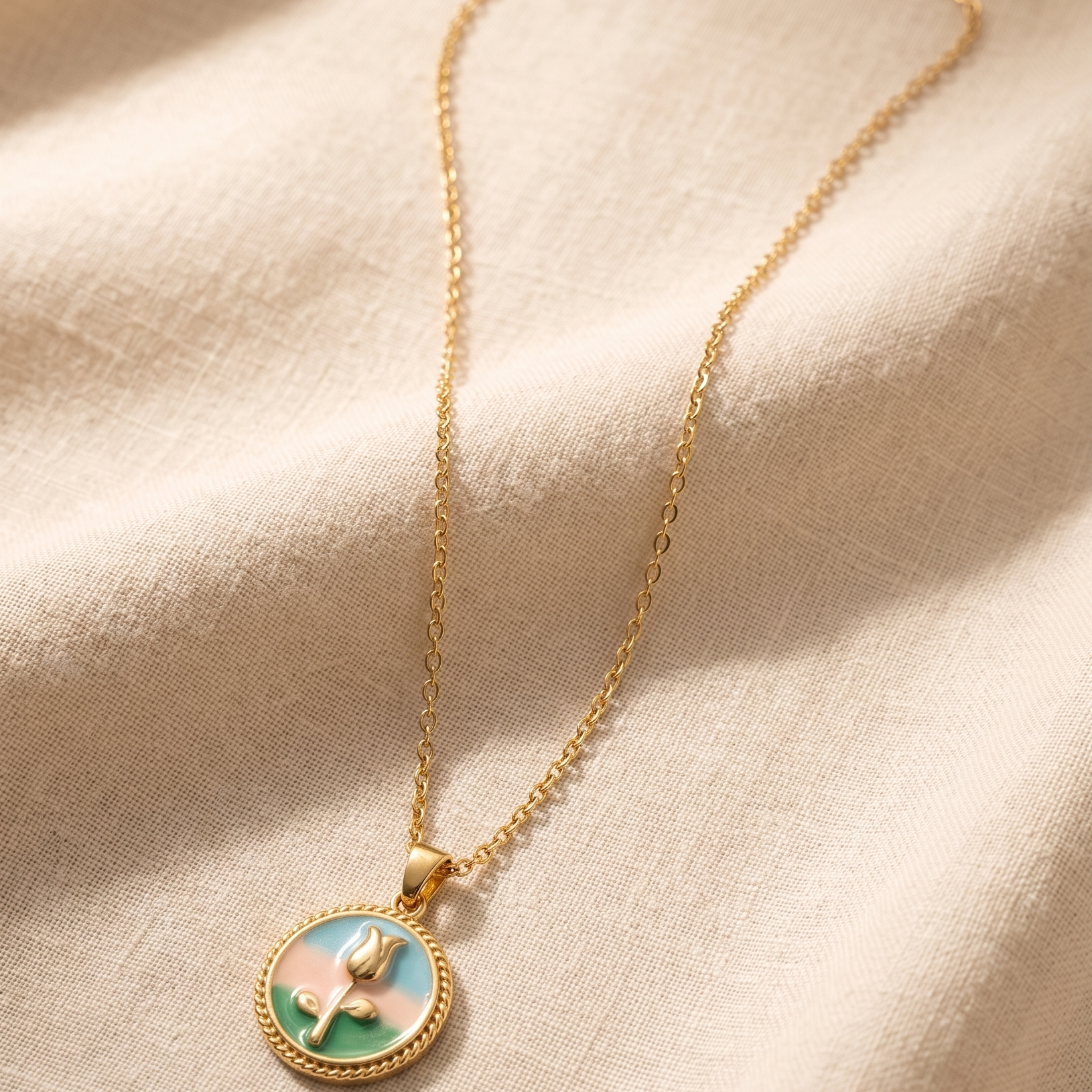 Gold necklace with a decorative pendant on a beige fabric background