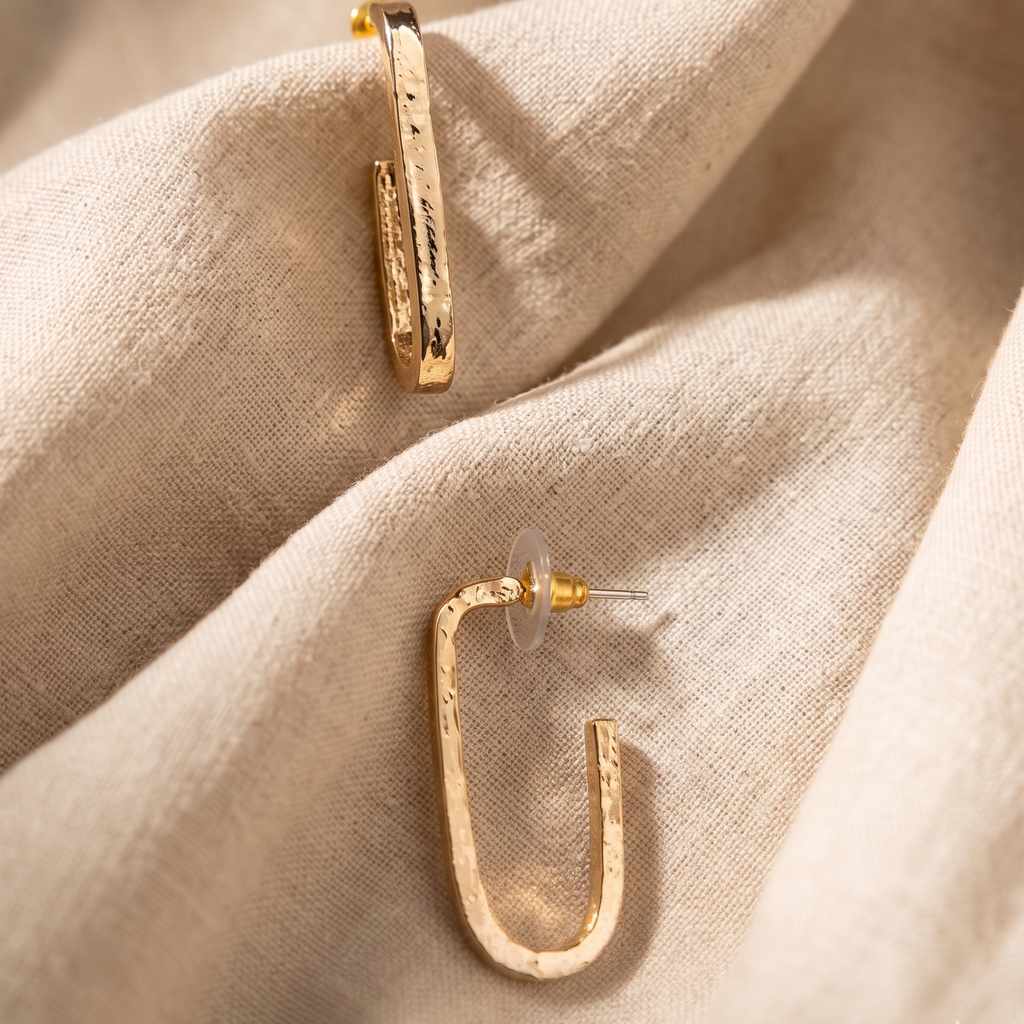 Gold hoop earrings on a beige fabric background
