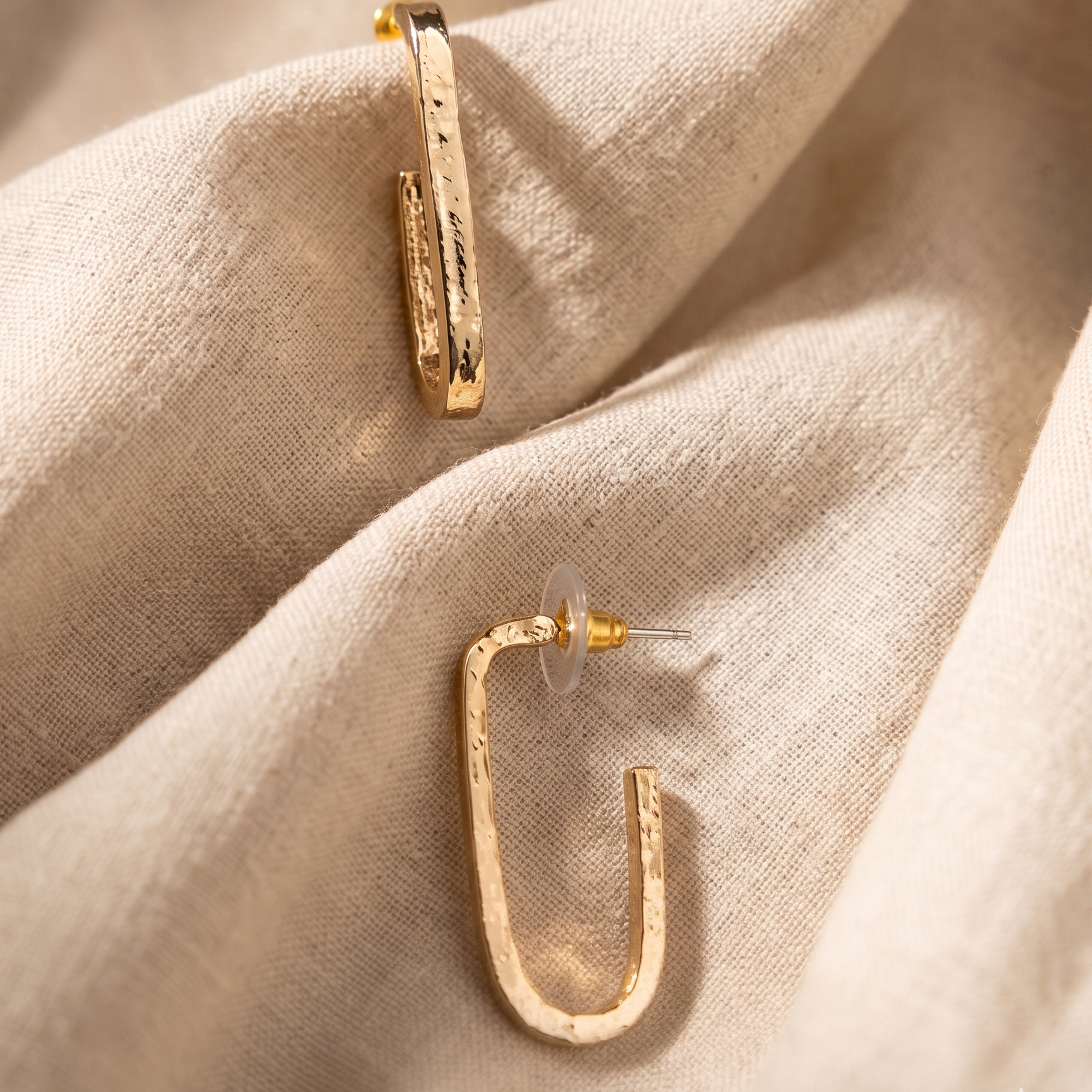 Gold hoop earrings on a beige fabric background