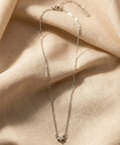 Delicate silver necklace on a soft beige fabric background