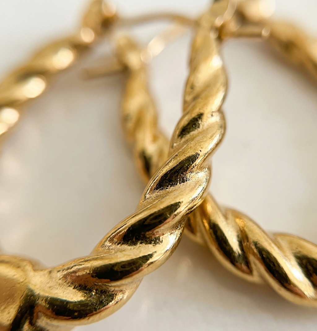 Close-up of gold hoop earrings on a light background