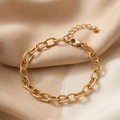 Gold chain bracelet on a beige fabric background