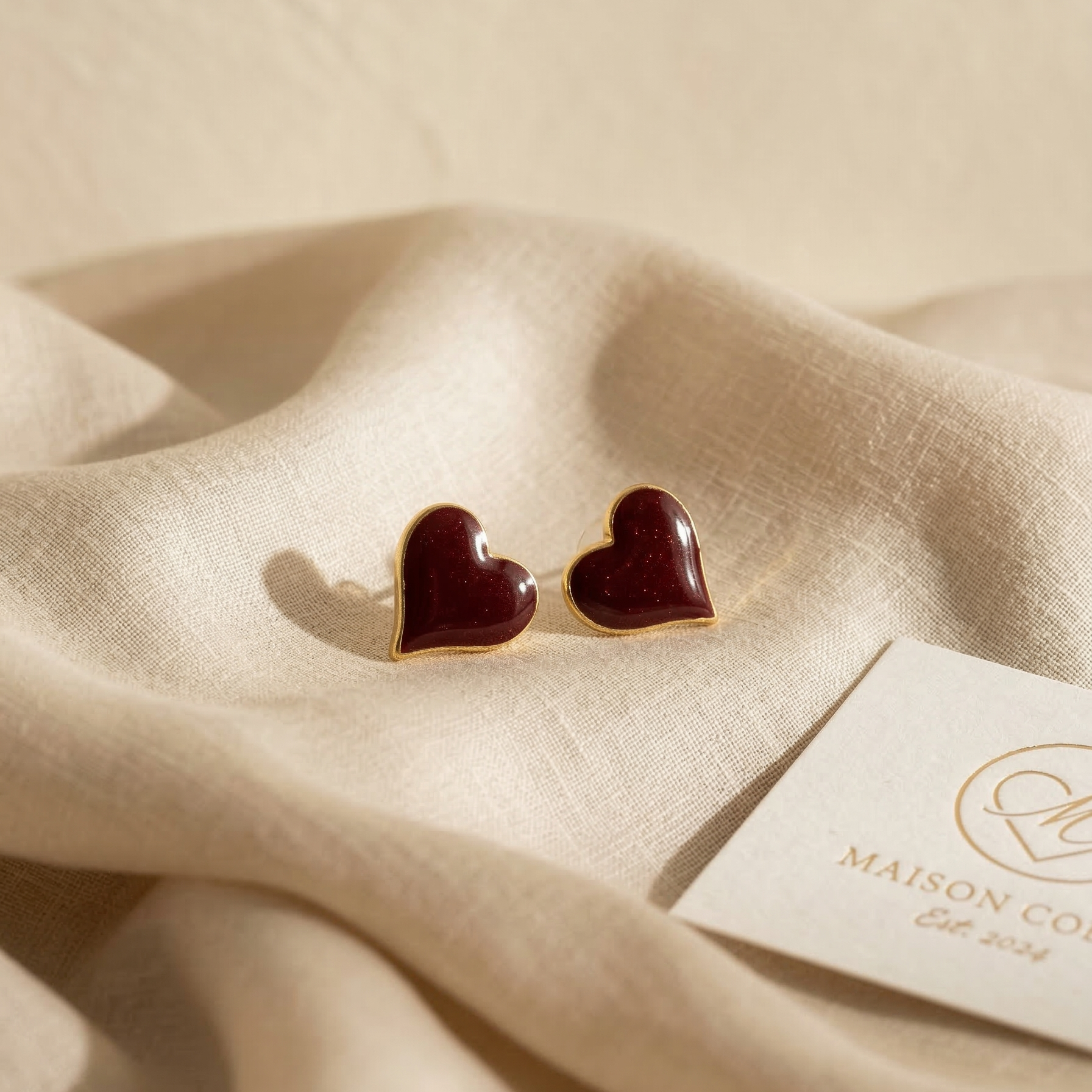 Heart-shaped earrings on beige fabric with a Maison Co tag