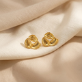 Gold earrings on a beige fabric background