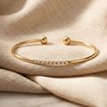 Gold bracelet with small diamonds on beige fabric