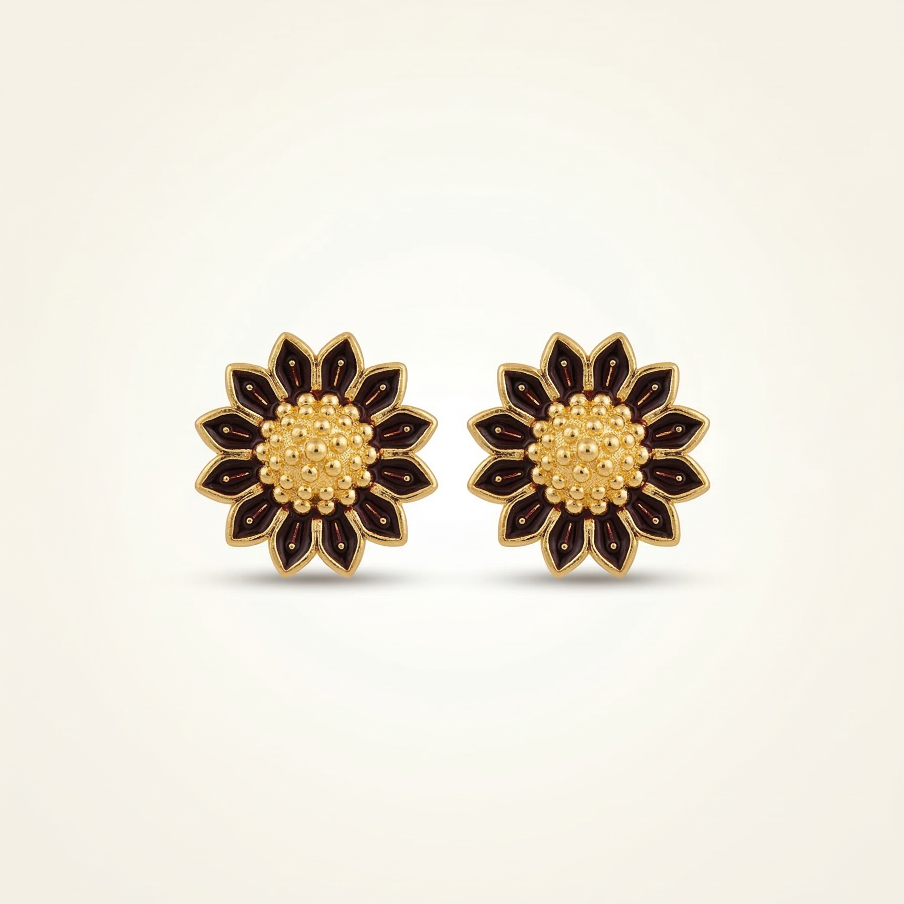Pair of floral earrings with gold and black design on a beige background
