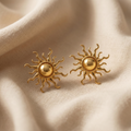 Gold sun-shaped earrings on beige fabric