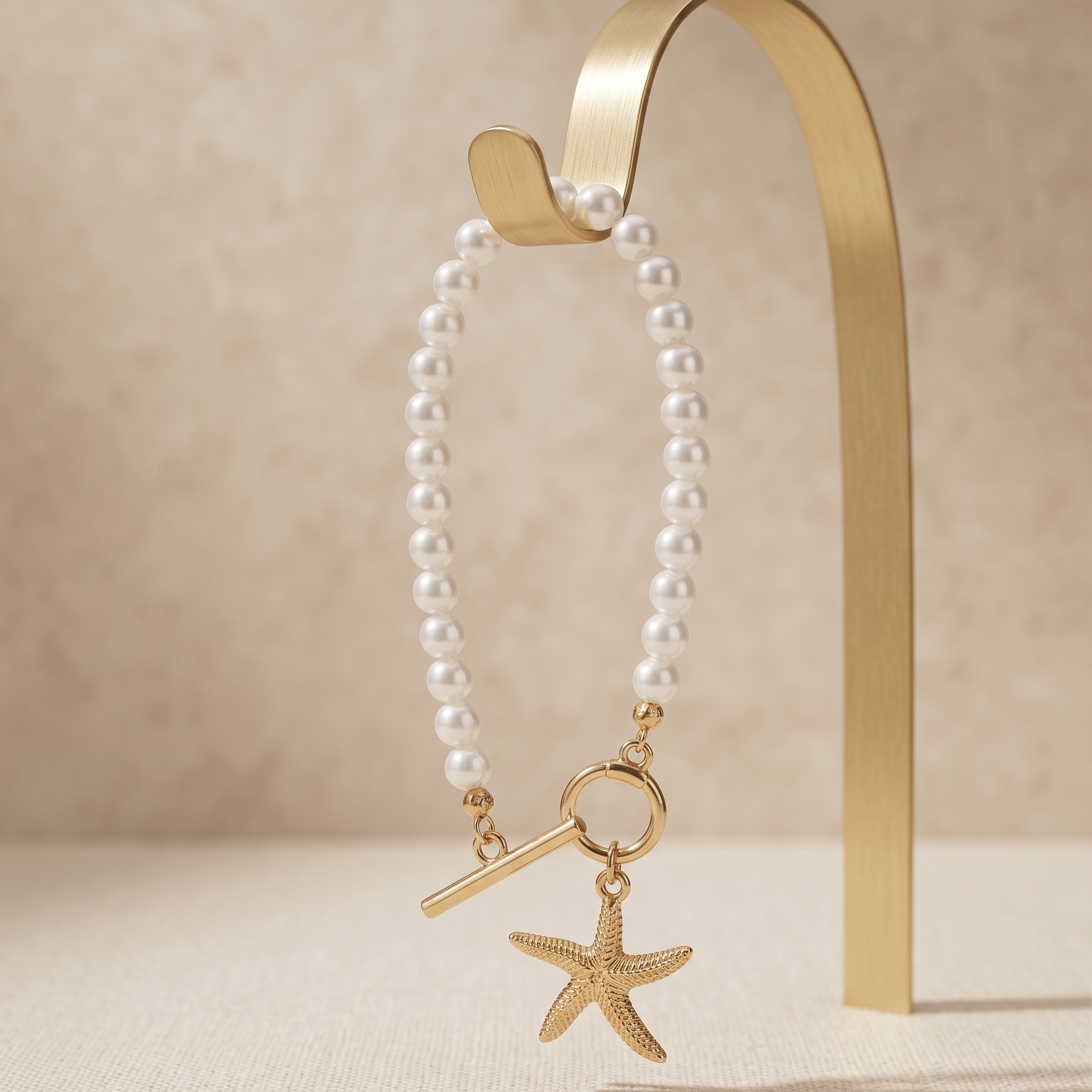 Pearl necklace with a gold starfish charm on a beige background