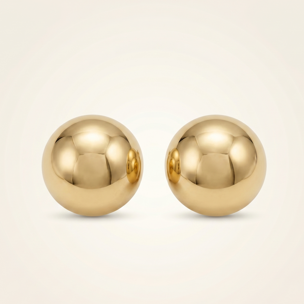 Pair of gold spherical earrings on a beige background