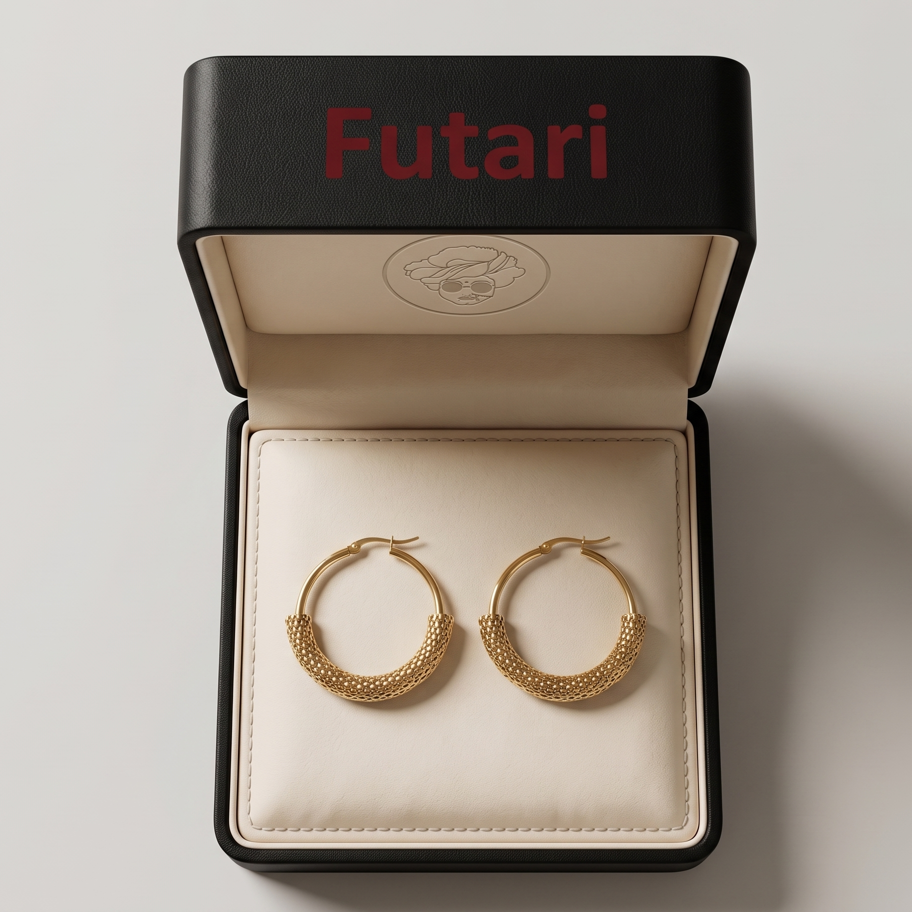 Gold hoop earrings in a 'Futari' jewelry box on a light gray background