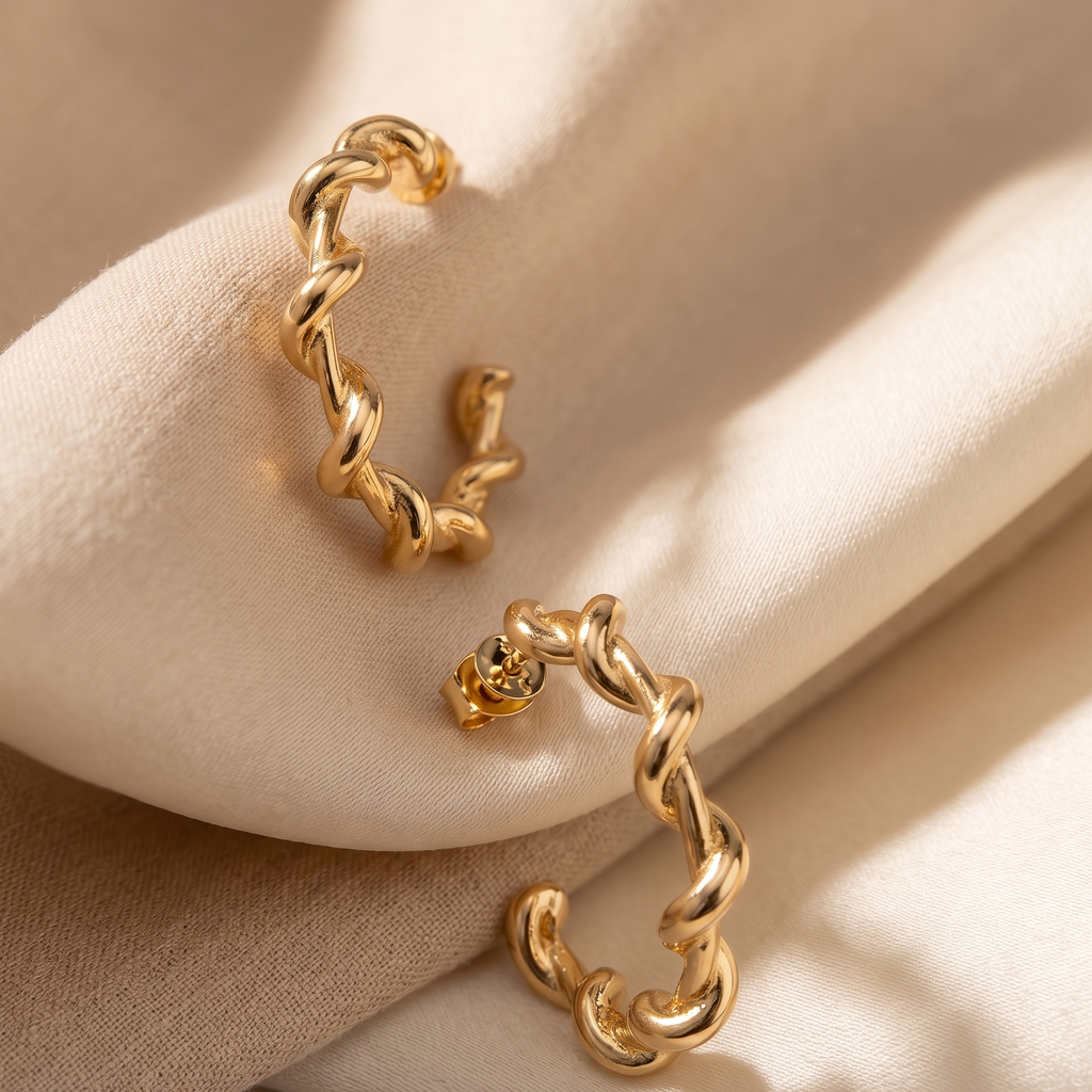 Gold hoop earrings on a beige fabric background