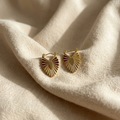 Gold earrings on a beige fabric background