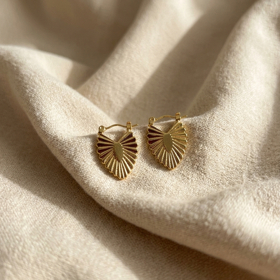 Gold earrings on a beige fabric background