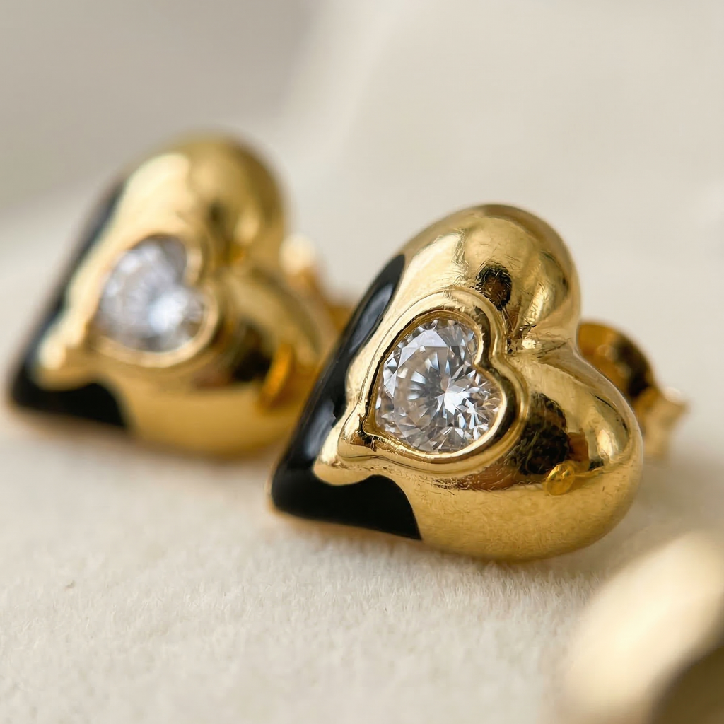 Gold heart-shaped earrings with clear gemstones on a beige background