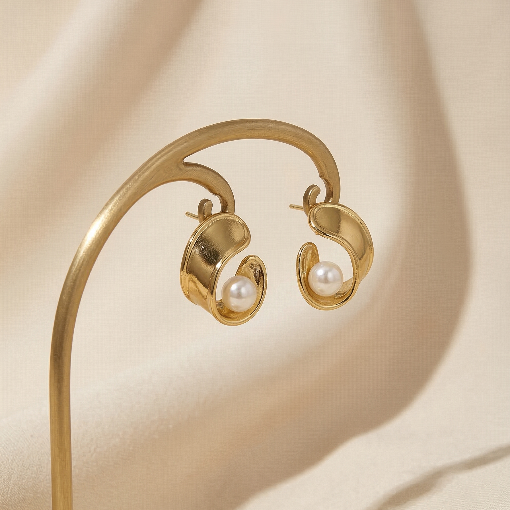 Gold earrings with pearls on a beige background
