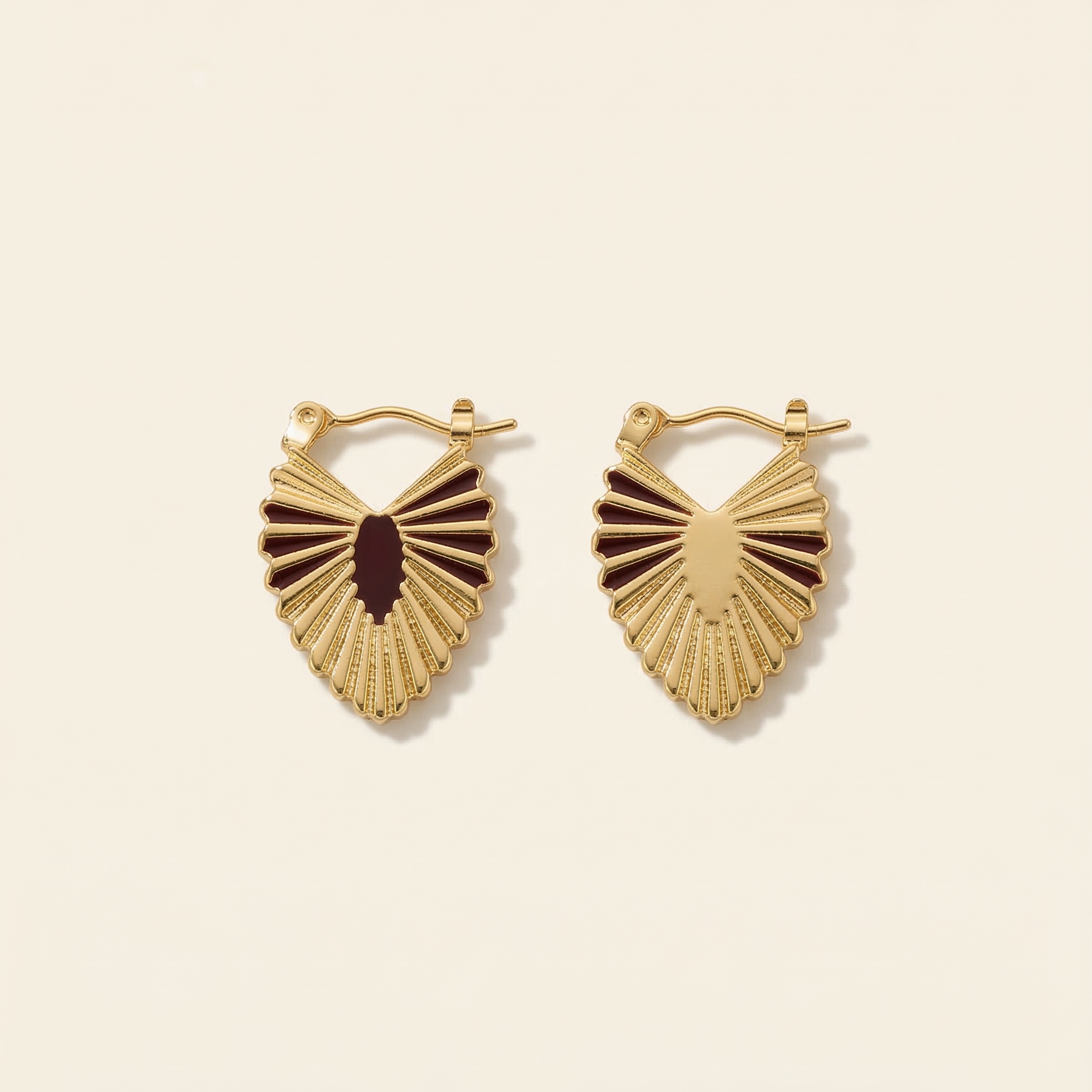 Gold heart-shaped earrings on a beige background